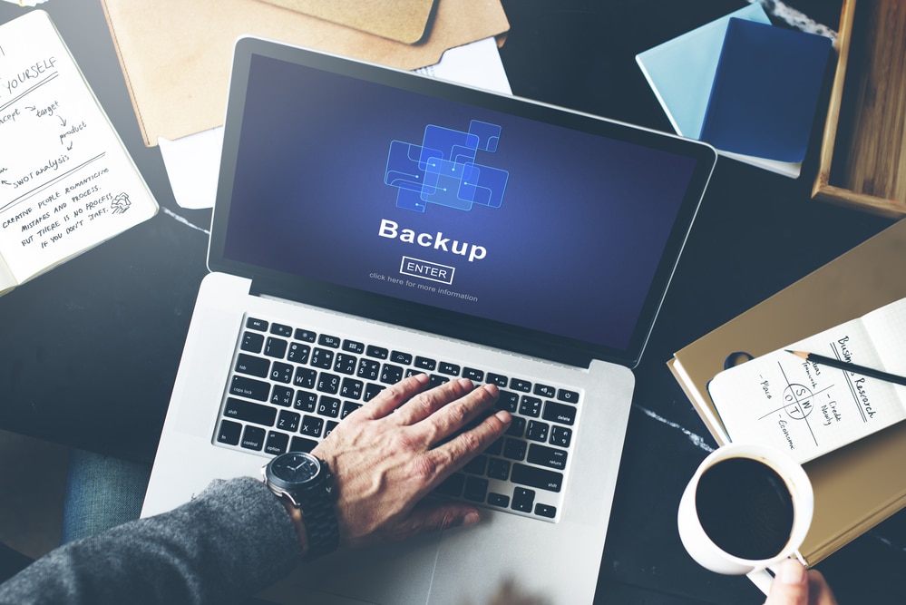 A man has his hand on the laptop while he on computer backup concept image on how to manually restore WordPress backup