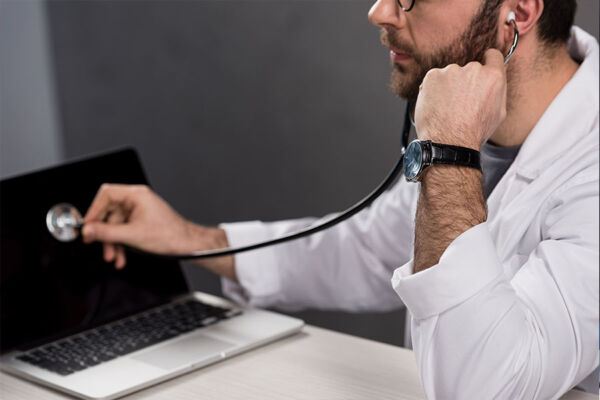 Technician in stethoscope examining laptop screen concept image for diagnosing theme issues